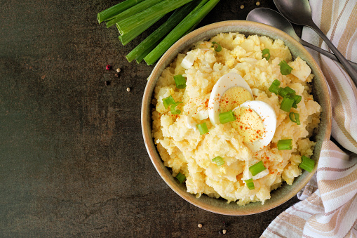 Traditional potato salad. Top down table scene on a dark stone background. Copy space.