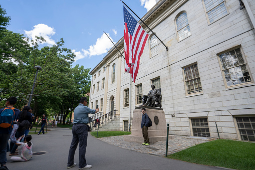 A large USA flag of stars and stripes flying high in strong wind on a sunny day in springtime.