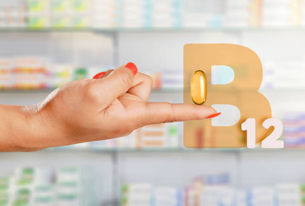 Female hand floating giant pill with Vitamin B-12 in pharmacy stock photo