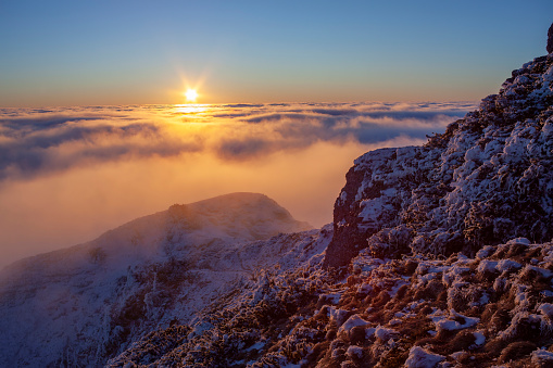 sunset on mountain top with clouds sea. winter scene