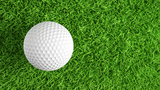 Close up on dirty golf ball on a tee with grass around.