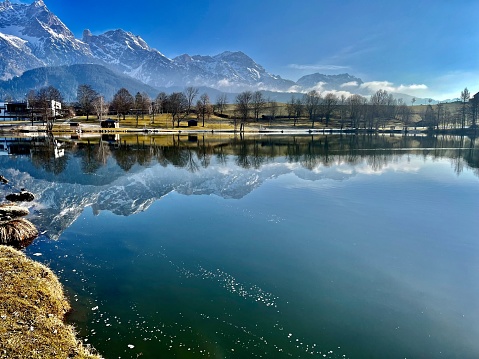 Schneebedeckte Berge in österreichischen Alpen reflektieren sich in See mit blauem Himmel