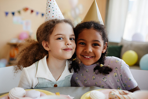 Portrait of two happy little girls looking at camera while enjoying birthday party together.