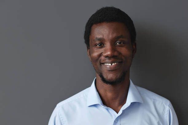 istock Black young businessman smiling at camera against wall 1495696944