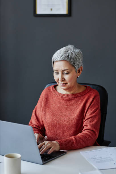 istock Senior businesswoman using laptop at workplace in office 1495696975