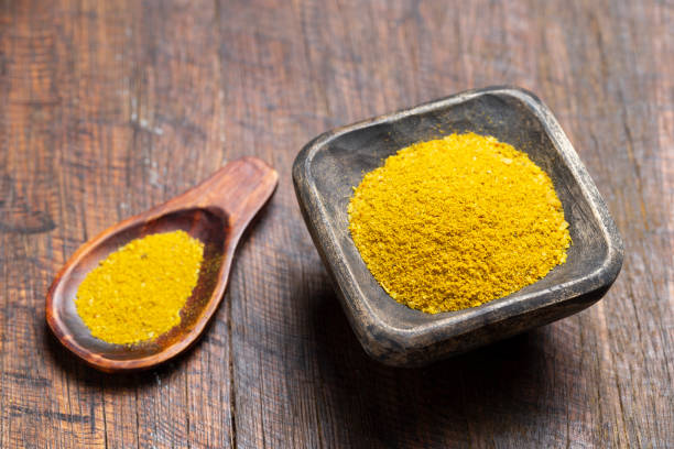 Turmeric, pepper and curry powder in container on wooden background