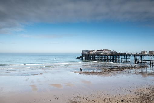 Sandy beach and the grade II listed seaside pier at Cromer in Norfolk England. The pier includes a Lifeboat Station and the Pavilion Theatre.