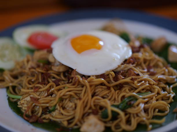 istock Selective focus Indonesian fried noodle with sunny side up egg served in banana leaf on plate. 1495710097