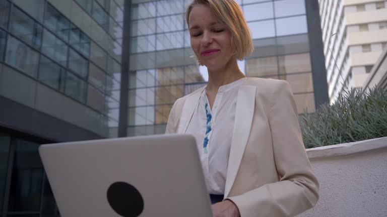 Caucasian businesswoman working outdoors using computer to be connected at all times.