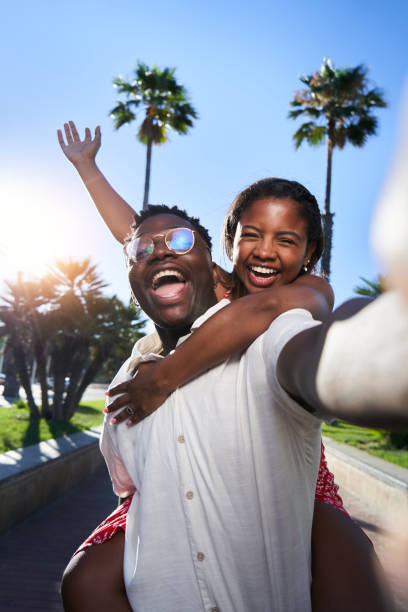 Cheerful selfie of a young African American couple on their summer vacation on an island. Cheerful selfie of a young African American couple on their summer vacation on an island. African man giving piggyback ride to his Latina girlfriend. Social media sharing. man video call pov stock pictures, royalty-free photos & images