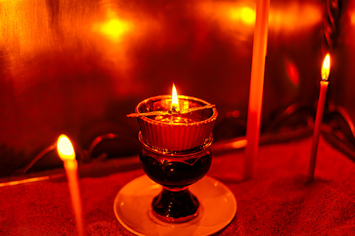 Red candle light Christmas candlelight on glowing flame sparkling green background blurred