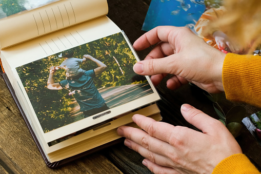 Photo printing. Young woman adding printed photo to family picture album.