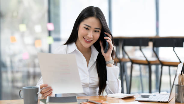 istock Successful businesswoman using mobile phone while working on e-business at office. 1495741748