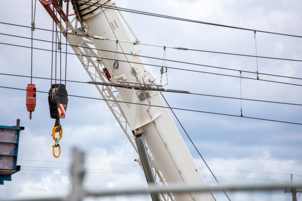 istock White crane boom with yellow hooks and train power lines. 1495759636