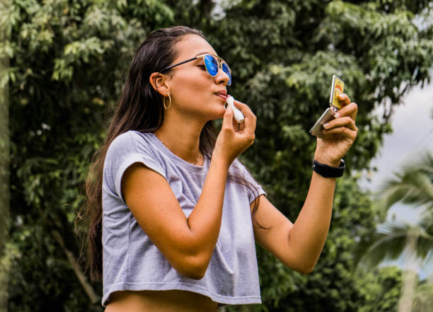 istock young woman looking at herself in a mirror applying lip gloss 1495759960