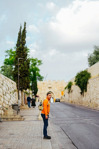 asian man walking a told city of Jerusalem corridor