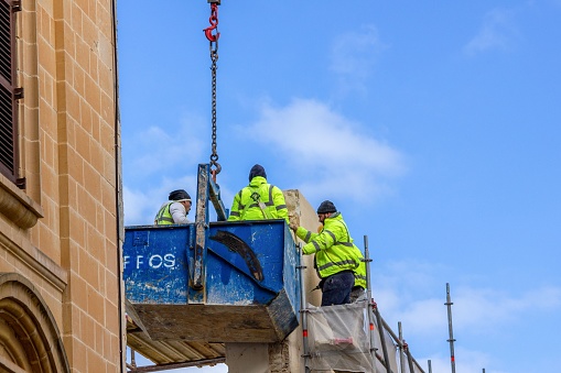 Valletta, Malta – January 28, 2022: The workers on a raised platform, lifting off a large, rectangular structure