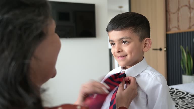 Mother helping young son with necktie