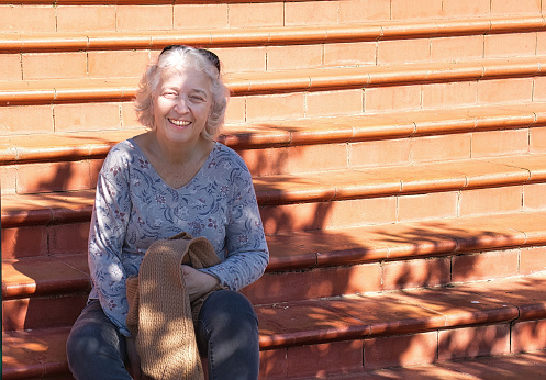 Portrait of a smiling elderly woman on the steps on a sunny day.