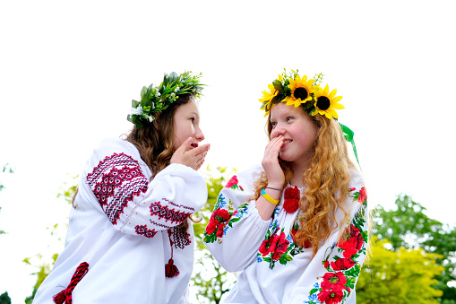 Two girls dress each other with a wreath of wildflowers. Weaving a wreath. A young pagan Slavic girl performs a ceremony on Midsummer Day. Earth Day. High quality