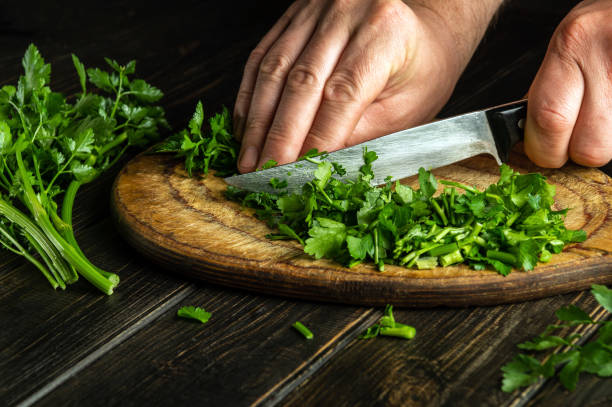 istock Chef cutting green parsley on a cutting board with a knife for preparing a vegetarian dish. Peasant food. 1495807701