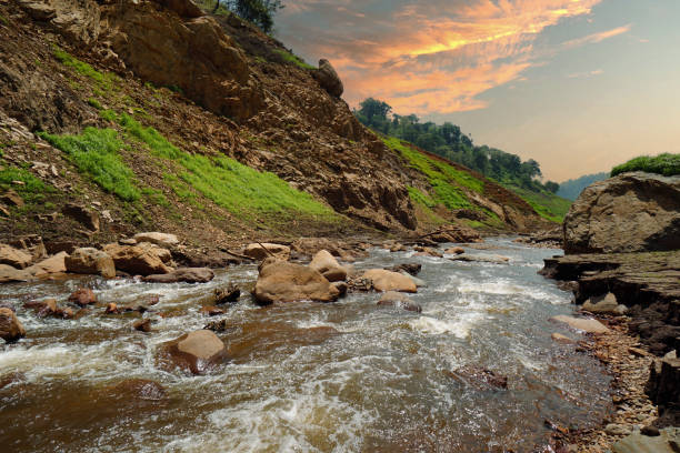 istock Upstream view on the dam's crest with a long-tailed boat. Surrounded by mountains and lush nature. 1495807784
