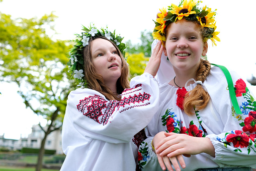 braiding braid girl with red hair in wreaths of sunflowers bright with girlfriend beautiful young woman braiding each other's hair decorate dressing preparing for celebration Ukrainian holiday