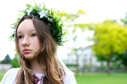 Portrait of a beautiful girl wearing a crown of chamomile. Little girl with a wreath of flowers on her head. High quality photo