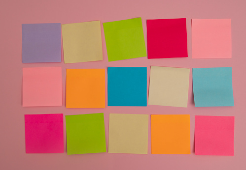 Colorful sticky notes isolated on pink background.