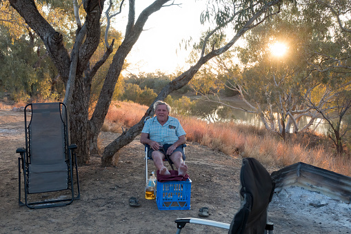 Senior man sitting near water in outback Queensland
