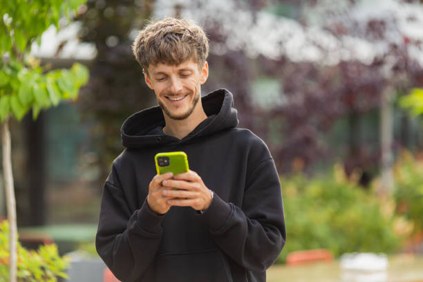 istock Happy young man with smartphone outdoors. Blurred summer background. Mobile phone 1495831004