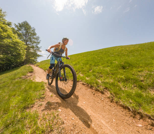 Woman riding mountain bike on trail stock photo