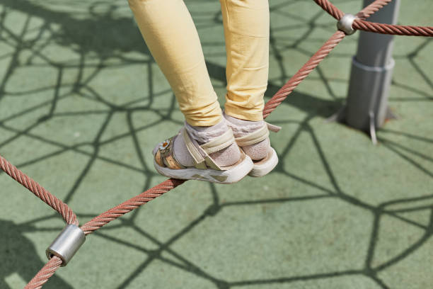 istock Legs of unrecognizable kid playing on playground walking on rope. 1495836674