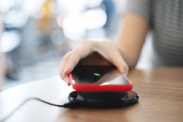 istock Woman charging mobile phone with wireless fast charger pad on desktop. 1495841065