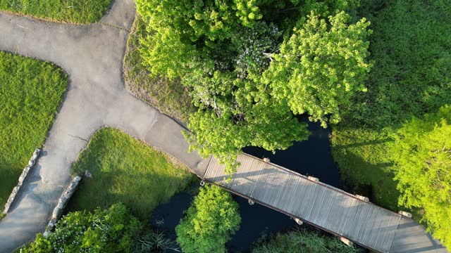 Drone moving down over a small wood bridge over a steam in a local park