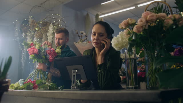 Female florist talks by phone and takes online order using tablet