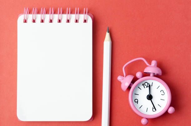 istock The Blank open diary and Alarm clock with pencil on red colored background 1495858294