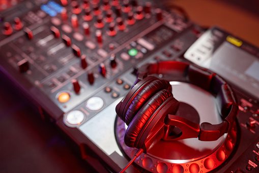 Close up background image of DJ equipment, mixer or turntable in neon light, copy space