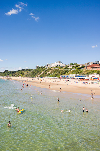 BOURNEMOUTH, UK - July 08, 2022. People enjoying summer by the sea on a sandy beach. Bournemouth, Dorset, UK