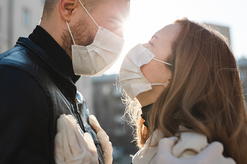 Couple in love, man and woman kissing each other in protective medical mask on face. Guy, girl against pandemic coronavirus, virus protection. Covid19.