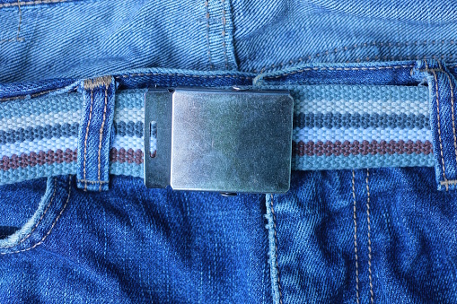 striped belt with gray metal buckle on blue jeans fabric