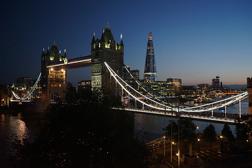 Illuminated iconic Tower Bridge in London at twilight under dramatic skyscape. London, United Kingdom, Europe.