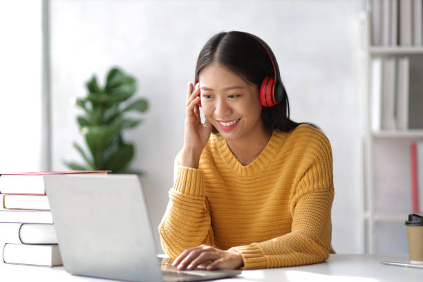 istock Young woman in university library working with laptop and reading a book. 1495874930