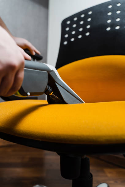 istock Housekeeper is extracting dirt from yellow armchair using dry cleaning extraction machine. Cleaner is cleaning chair with washing vacuum cleaner extractor machine for dry clean upholstered furniture. 1495876359