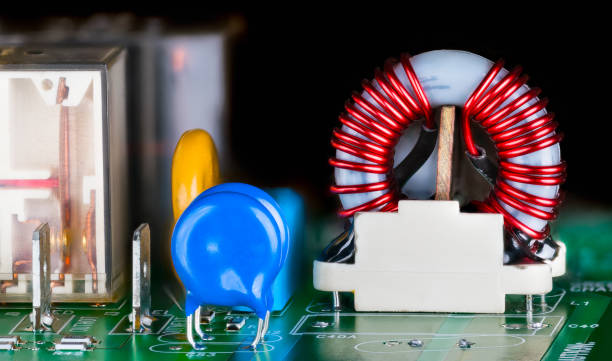 primo piano della bobina del nucleo toroidale nel circuito stampato elettronico su uno sfondo nero - service electronics industry circuit board capacitor foto e immagini stock