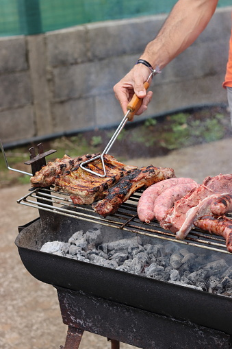 Man cooking pork rib, sausage and grilled beef churrasco on a barbecue. Vertical image.