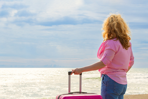 Woman with luggage enjoying the beach view, Seashore travel, Beach vacation