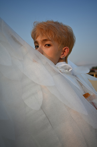 Portrait with stylish Asian teenage boy wear angel wings costume, wings on the foreground.