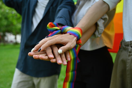 Close up and cropped with a group of hands with rainbow wristband join hands together, Support and celebrate the LGBT community.
