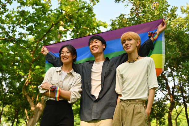 feiern sie den pride month mit jungen lgbt-männern und -frauen, die stolz stehen und regenbogenflaggen halten. - adolescence flag university people stock-fotos und bilder